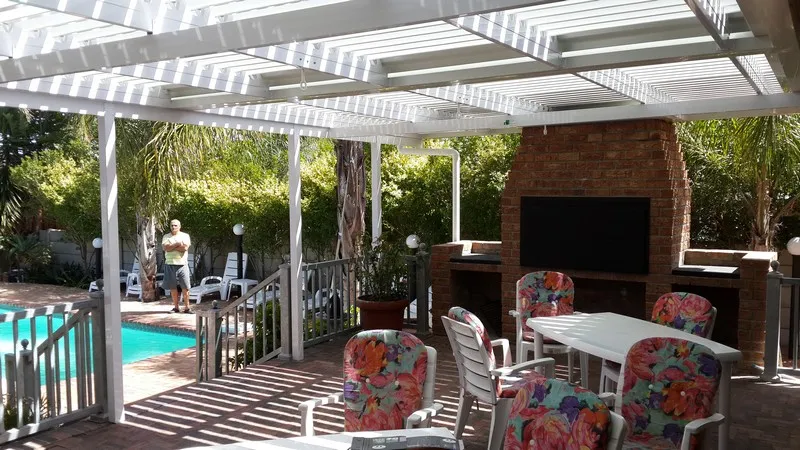 Charcoal-framed adjustable louvre awning over a contemporary terrace