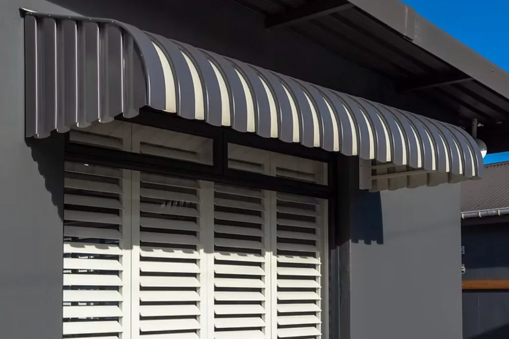 Charcoal and cream fixed aluminium window awning over a shuttered window on a modern plastered home
